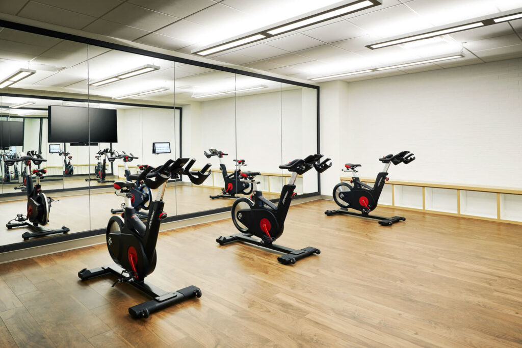 Three stationary bikes in front of mirror